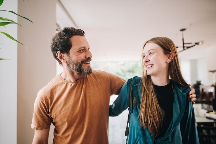 Father and teen daughter talking while walking at home